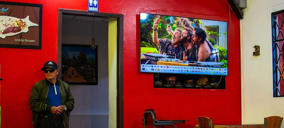 Interior of a restaurant in Loja, Ecuador. On the left, an older man wearing sunglasses stands near the entrance to the bathrooms,